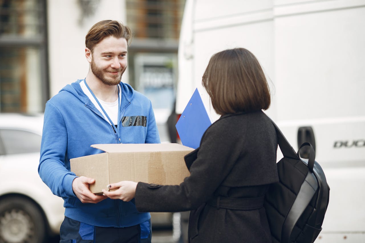 Candid moment of a deliveryman handing a package to a woman outside by a van.